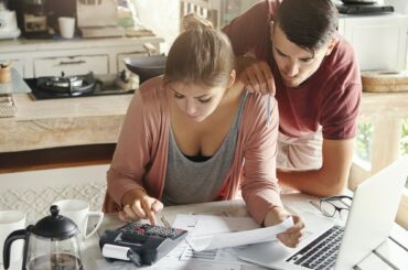 Family budget and finances concept. Young serious wife and husband doing accounts together at home,